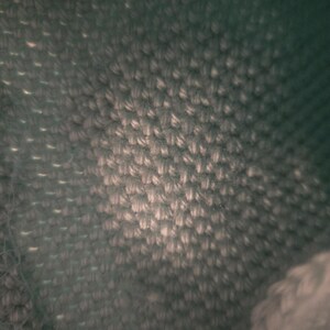 Puede incluir: Primer plano de una tela verde oscuro con un patr&oacute;n tejido texturizado.