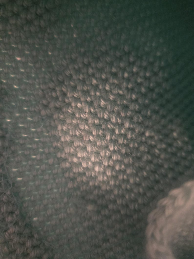 Puede incluir: Primer plano de una tela verde oscuro con un patr&oacute;n tejido texturizado.