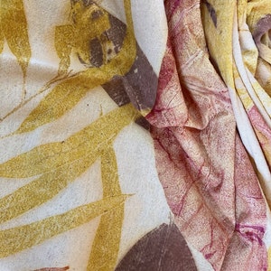 May include: A white fabric with a natural, textured surface. The fabric is decorated with a leaf pattern in shades of brown, yellow, and red.