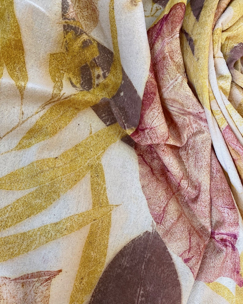 May include: A white fabric with a natural, textured surface. The fabric is decorated with a leaf pattern in shades of brown, yellow, and red.