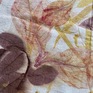 May include: A close-up of a fabric with a leaf print. The leaves are in shades of brown, yellow, and pink. The fabric has a textured surface.