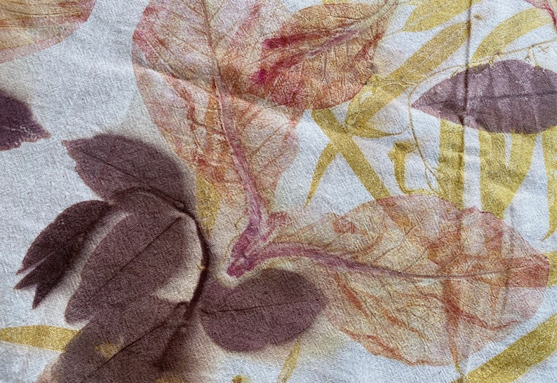 May include: A close-up of a fabric with a leaf print. The leaves are in shades of brown, yellow, and pink. The fabric has a textured surface.