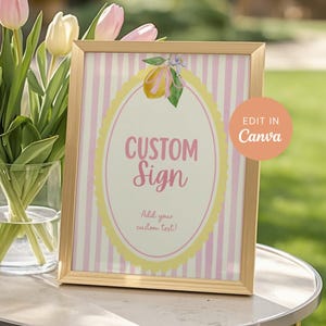 May include: A framed custom sign with a pink and white striped background. The sign features the words "CUSTOM Sign" in pink script within a yellow oval, with the text "Add your custom text!" below. A floral lemon illustration is at the top.