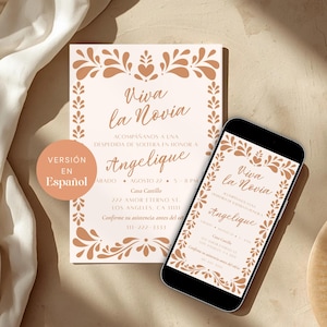 Op de afbeelding: Een trouwuitnodiging en een smartphone met hetzelfde ontwerp. De uitnodiging en het telefoonscherm tonen de tekst "Viva la Novia" in elegant schrift, omlijst door een decoratieve bloemenrand in perzik- en bruintinten.