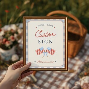 Hand holding framed customizable party sign at Fourth of July Americana celebration setup