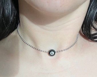 May include: A silver chain necklace with a black and white 8-ball charm.
