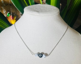 May include: A silver chain necklace with a black and white 8 ball charm and two white dice charms.