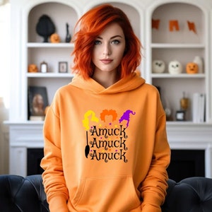 May include: Orange hoodie with a graphic of three witches with the text "Amuuck Amuuck Amuuck" printed on the front.