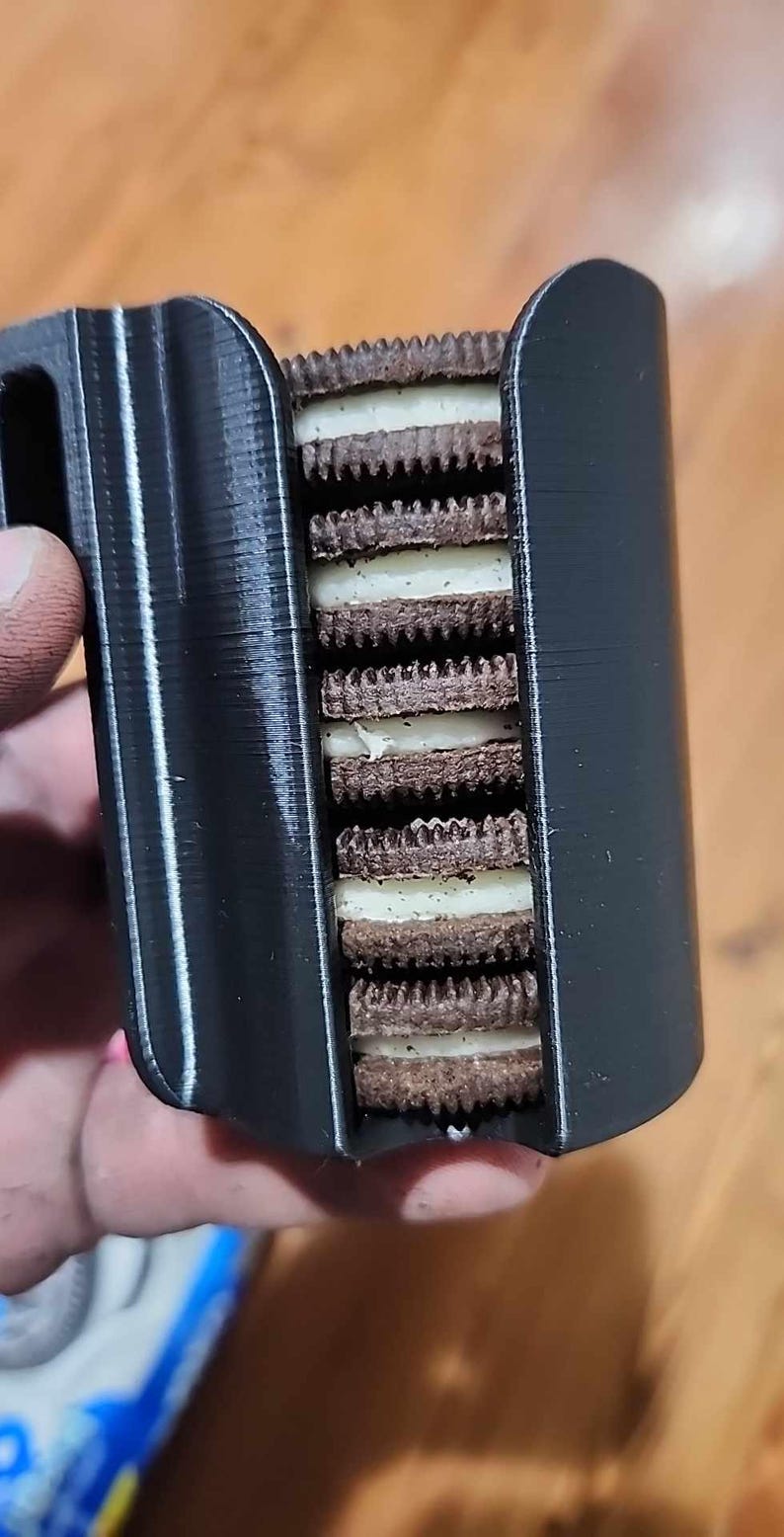 May include: A black 3D printed mug holder with a stack of Oreo cookies inside.