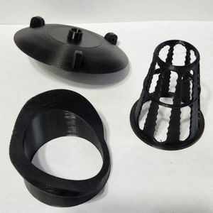 Pode incluir: Três peças pretas impressas em 3D para um foguete modelo. As peças incluem um cone de nariz cônico, uma base circular e uma peça em forma de anel.