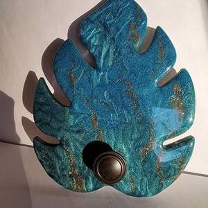 May include: A teal blue resin leaf with gold glitter accents and a brown knob in the center.