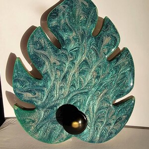 May include: A teal green leaf-shaped tray with a swirling pattern and a black resin accent.