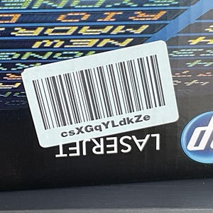 May include: A black HP LaserJet printer box with a white barcode label and the text "csXGgYLdkZe". The HP logo is visible on the lower right corner. The box has a background of city names.