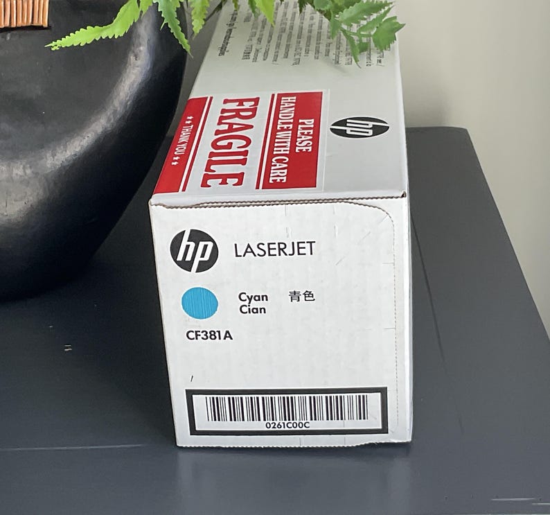 May include: A white HP LaserJet printer cartridge box with red "FRAGILE" and "HANDLE WITH CARE" labels. The box features the HP logo, the word "LASERJET", and "Cyan" in English and Chinese. The model number CF381A is also visible.