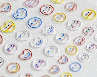 May include: A sheet of clear stickers with colourful smiley faces, hearts, and other designs. The stickers are on a white background. The text on the sticker sheet reads "10 541"