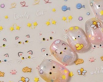 May include: A sheet of clear nail stickers with a variety of cute cat faces, stars, and other designs. The stickers are on a white background and have a pink and yellow color scheme. The text "to 3906" and "猫爪美甲贴纸" are printed on the sheet.
