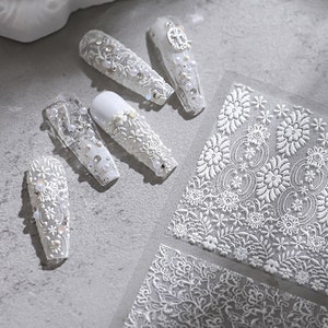 Puede incluir: Pegatinas blancas para nail art con un delicado diseño de encaje. Las pegatinas presentan un patrón floral con un efecto 3D.