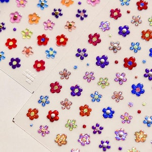 May include: A sheet of colorful flower stickers with glitter and pearl accents. The stickers are arranged in rows and are ready to be used for crafts, scrapbooking, or decorating.