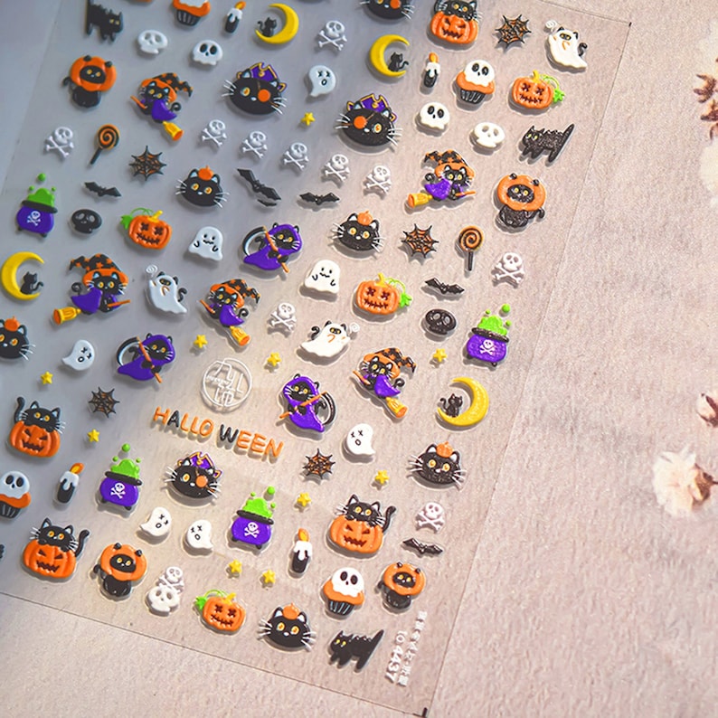 Peut inclure: Une feuille d'autocollants pour ongles sur le th&egrave;me d'Halloween avec des chats noirs, des citrouilles, des fant&ocirc;mes, des chauves-souris, des &eacute;toiles, des lunes et des bonbons. Les autocollants comprennent &eacute;galement le texte "HALLOWEEN".