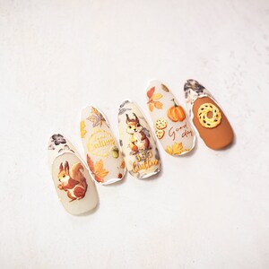 Puede incluir: Cinco dise&ntilde;os de u&ntilde;as con tem&aacute;tica oto&ntilde;al que incluyen una ardilla, hojas, calabazas y el texto "Good day" y "Fall Autumn".