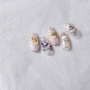 May include: Five clear nail polish colors with glitter and cat designs. The designs include a cat face, a cat paw print, and a cat tail.