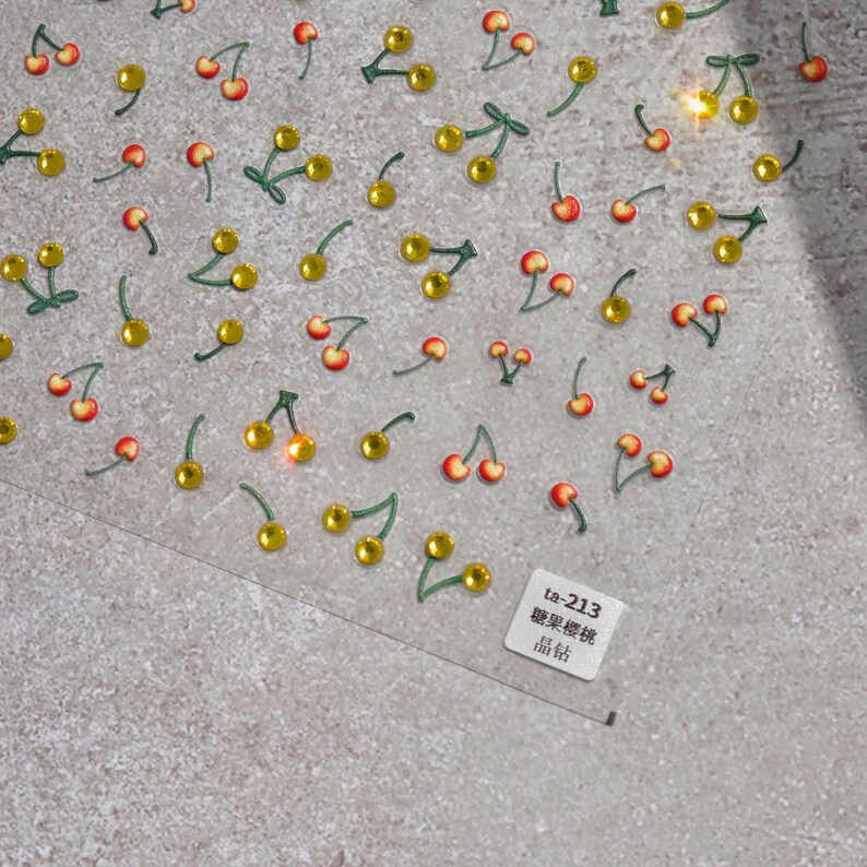 May include: A sheet of clear adhesive stickers with a repeating pattern of red cherries with green stems and yellow leaves. The sheet has the text "ta-213  樱桃贴纸  贴纸  162" printed on it.