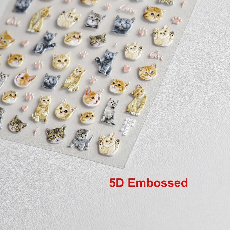 May include: A sheet of clear plastic with 3D embossed stickers of cats in various poses. The stickers are in shades of brown, gray, and white. The sheet has a pink paw print design and the text "Cat" and "5D Embossed" printed on it.