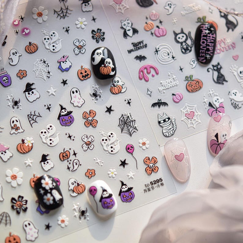 May include: Clear sheet of Halloween-themed nail art stickers. Designs include ghosts, pumpkins, spiders, bats, flowers, and cats. Some nails are painted with Halloween designs. The text "Happy Halloween" is visible.