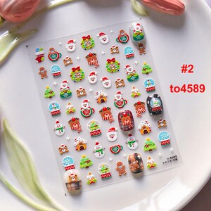 May include: A sheet of Christmas-themed nail stickers with a variety of designs, including snowmen, reindeer, gingerbread men, and Christmas trees. The stickers are on a clear background and are ready to be applied to nails. #2 to4589