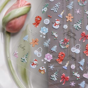 May include: A sheet of clear stickers with a variety of Christmas-themed illustrations, including snowmen, gingerbread men, snowflakes, trees, and ornaments. The stickers are printed in a variety of colors, including red, green, blue, and white. The text "Happy Christmas" and "Lucky" are also included on the sheet.