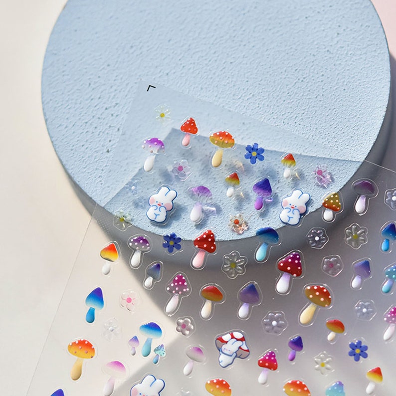 May include: A sheet of clear sticker paper with colorful mushroom and bunny stickers. The stickers are 3D and have a glossy finish.