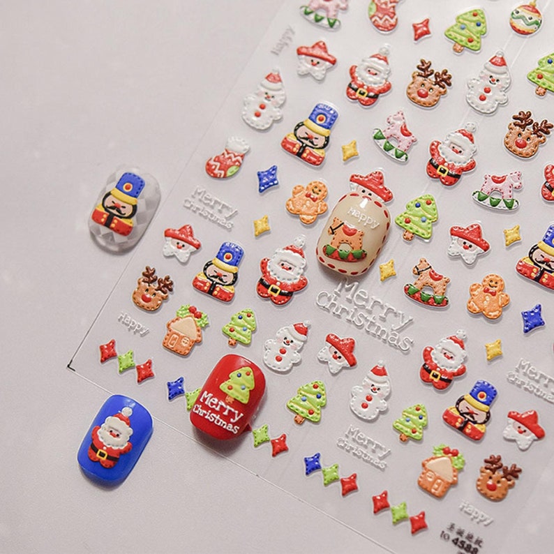 May include: A sheet of Christmas nail stickers with a variety of designs, including Santa Claus, Christmas trees, gingerbread men, and nutcrackers. The stickers are on a clear background and are ready to be applied to nails.