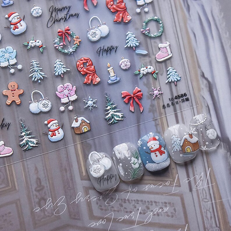 May include: A sheet of Christmas-themed nail stickers with images of snowmen, mittens, snowflakes, trees, candles, wreaths, and the words "Merry Christmas" and "Happy".
