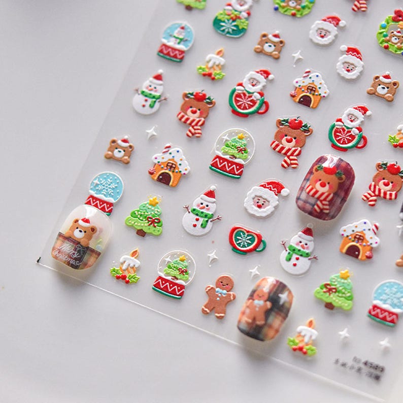 May include: A sheet of Christmas-themed nail stickers featuring a variety of designs, including snowmen, Christmas trees, gingerbread men, Santa Claus, and bears. The stickers are on a clear background and are ready to be applied to nails.