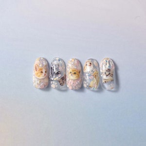 May include: Five clear nail polish bottles with glitter and cat designs. Each bottle has a different cat design.