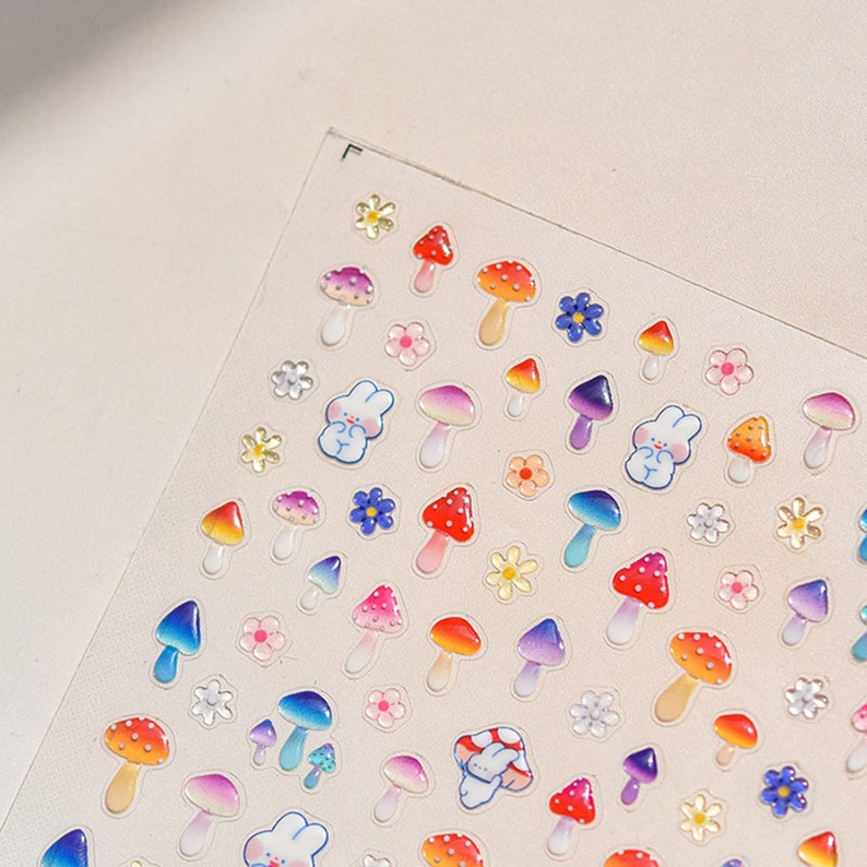 May include: A sheet of colorful mushroom and flower stickers. The stickers are glossy and have a 3D effect. There are red, orange, yellow, green, blue, and purple mushrooms. There are also white flowers with yellow centers.