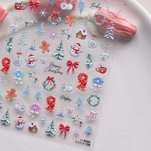 May include: A sheet of clear nail stickers with a variety of Christmas-themed designs, including snowmen, gingerbread men, presents, and wreaths. The stickers are printed with red, white, blue, and green colors. The text "Merry Christmas" and "Happy" are printed on the sheet.