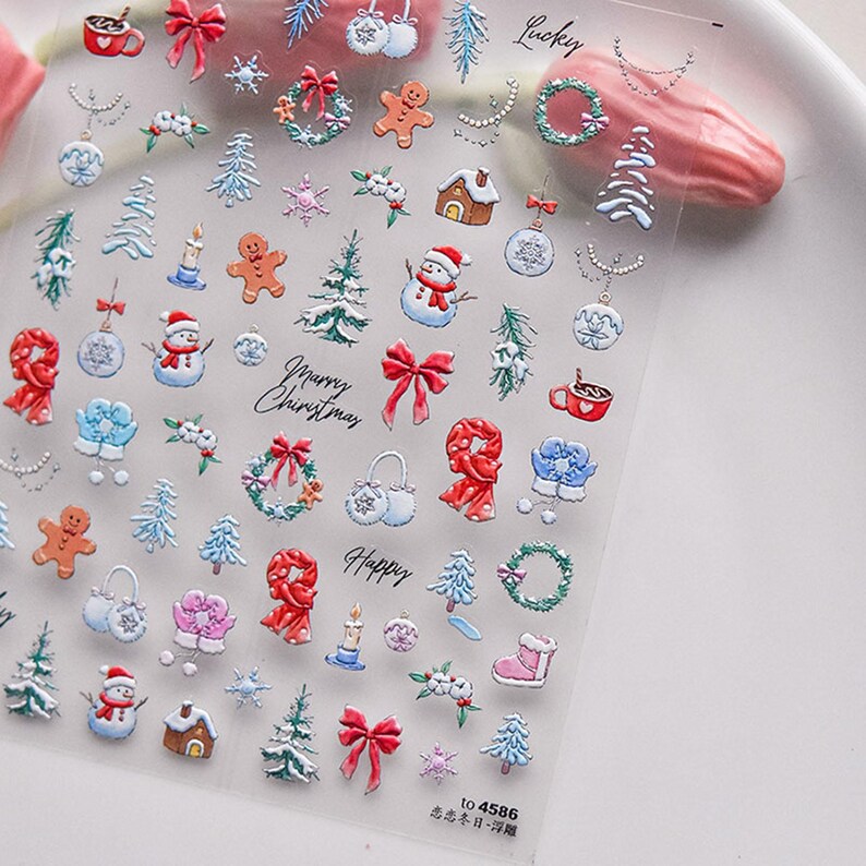 May include: A sheet of clear nail stickers with a variety of Christmas-themed designs, including snowmen, gingerbread men, presents, and wreaths. The stickers are printed with red, white, blue, and green colors. The text "Merry Christmas" and "Happy" are printed on the sheet.
