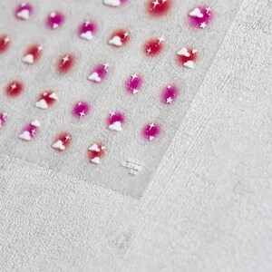 May include: A sheet of clear sticker paper with pink and white cloud and star stickers. The stickers are arranged in rows and columns.