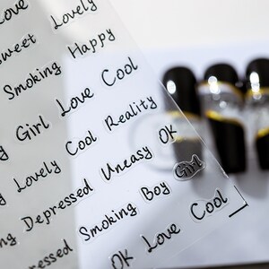 May include: A clear sheet with black text words printed on it. The words include "Love", "Smoking", "Happy", "Girl", "Cool", "Reality", "Depressed", "Uneasy", "OK", "Boy", and "Girl".