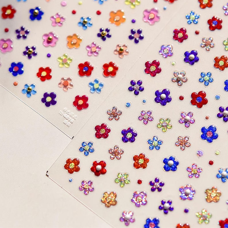 May include: A sheet of colorful flower stickers with glitter and pearl accents. The stickers are arranged in rows and are ready to be used for crafts, scrapbooking, or decorating.