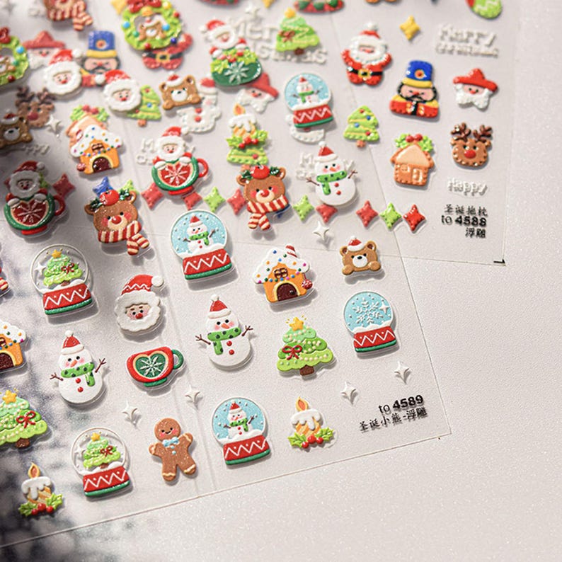 May include: A sheet of colorful Christmas-themed stickers featuring various holiday icons, including snowmen, Santa Claus, gingerbread men, Christmas trees, and snow globes. The stickers are arranged in rows and columns on a clear plastic sheet.