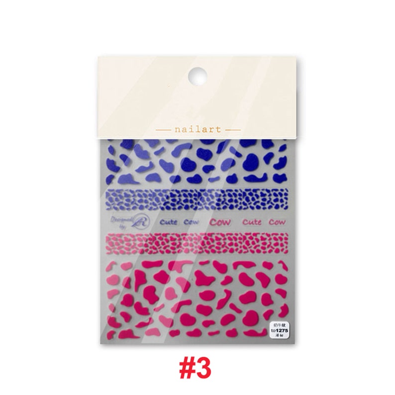 Op de afbeelding: Een pakketje met nagelstickers met een koe-print ontwerp. De stickers zijn blauw en roze en hebben de tekst "Cute Cow" erop. Het pakketje is gelabeld met het nummer "#3".