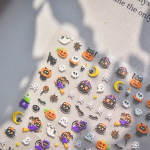 Peut inclure: Une feuille d'autocollants sur le th&egrave;me d'Halloween avec des chats noirs, des citrouilles, des fant&ocirc;mes, des cr&acirc;nes, des chauves-souris, des toiles d'araign&eacute;es et d'autres motifs effrayants. Les autocollants sont sur un fond transparent.