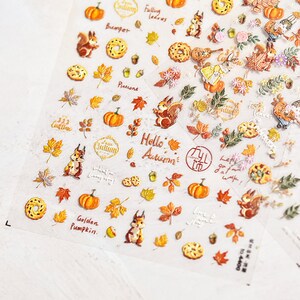 Puede incluir: Una hoja de pegatinas con tem&aacute;tica oto&ntilde;al con ardillas, calabazas, hojas, bellotas y otras im&aacute;genes de oto&ntilde;o. Las pegatinas est&aacute;n impresas con frases como "Hello Autumn", "Golden Pumpkin" y "Falling Leaves".