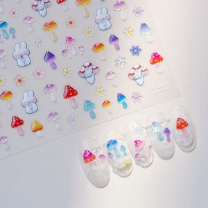 May include: A sheet of nail art stickers featuring colorful mushrooms, flowers, and bunnies. The stickers are designed to be applied to fingernails.