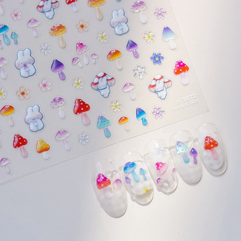 May include: A sheet of nail art stickers featuring colorful mushrooms, flowers, and bunnies. The stickers are designed to be applied to fingernails.