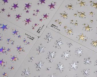 May include: Sheets of star-shaped nail art stickers in silver, gold, and iridescent purple. The stickers are arranged in various sizes and patterns on a white background. Some sheets have text.