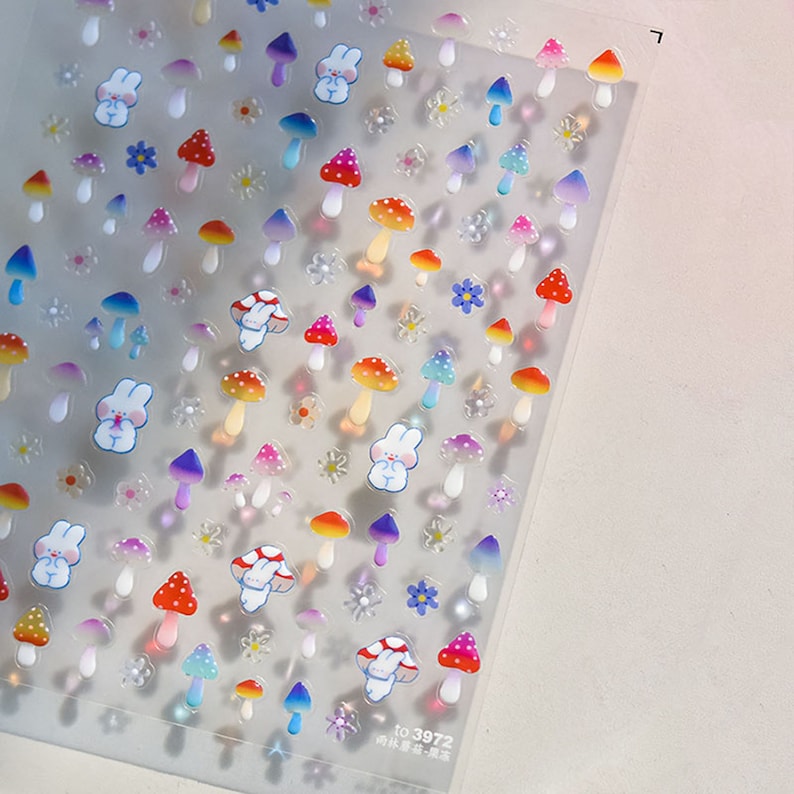 May include: A sheet of colorful, iridescent stickers featuring mushrooms, bunnies, and flowers. The stickers are perfect for adding a whimsical touch to journals, planners, and other craft projects.