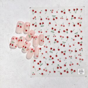 May include: A sheet of clear nail stickers with red and green cherry designs. The cherries have a single red rhinestone in the center. The sheet is labeled "ta-211  贴纸  贴纸".